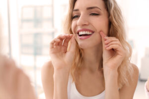 Young woman flossing her teeth indoors