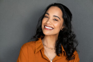 young woman smiling on grey background