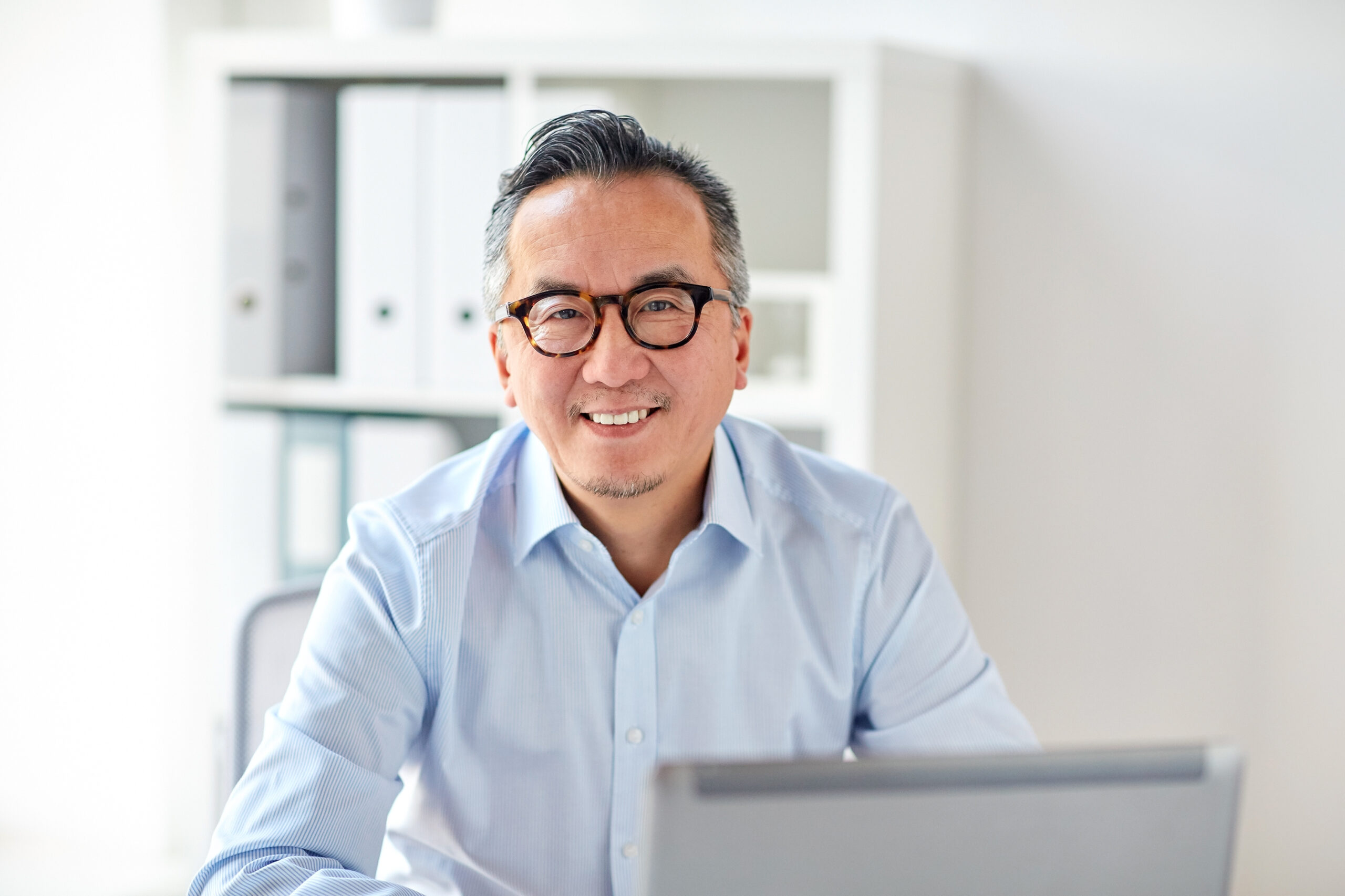 Man in glasses smiling over laptop
