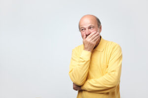 Older man covering mouth with hand