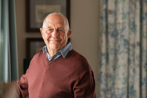 Senior man standing at home near window