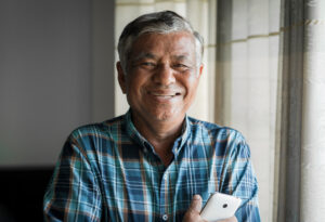 Older man smiling holding phone