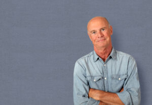 Portrait of senior man standing on grey background